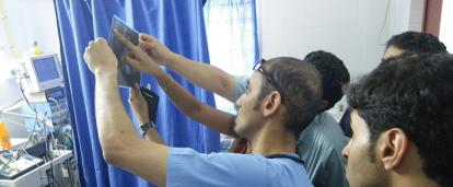 Projects Abroad interns observe a medical doctor as he describes the type of injuries sustained by a patient in India. Medical interns listen to a local doctor explain an injury in India.